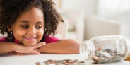 child looking at a jar of money