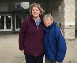 Trish and Edna standing in front of the prison they volunteer at