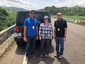 three people standing in front of a jeep