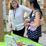 two women standing looking at plants and books on a table