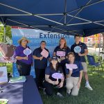 group of people standing under a tent with Earth Day signs