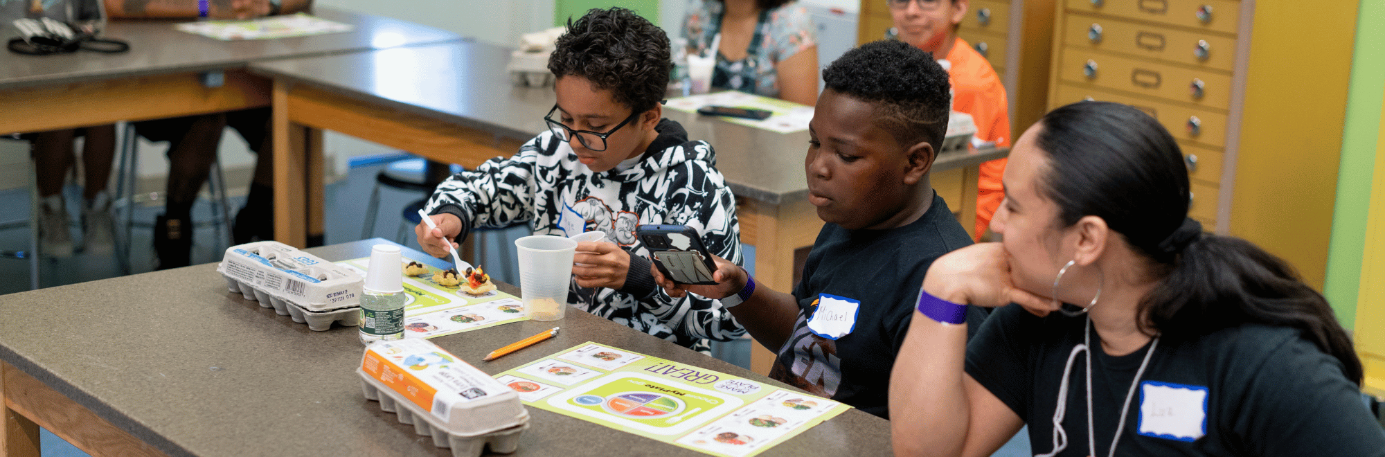 2 kids and an adult with food and eggs in front of them, learning about nutrition with a my plate placemat