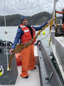 Anoushka holding a long piece of seaweed on a boat