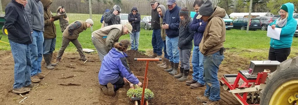 people standing around a women teaching how to plant a plot
