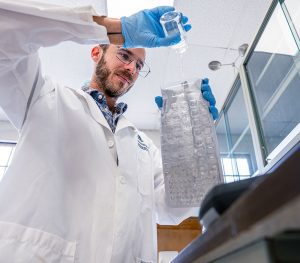 man in a lab pouring water into a bag.