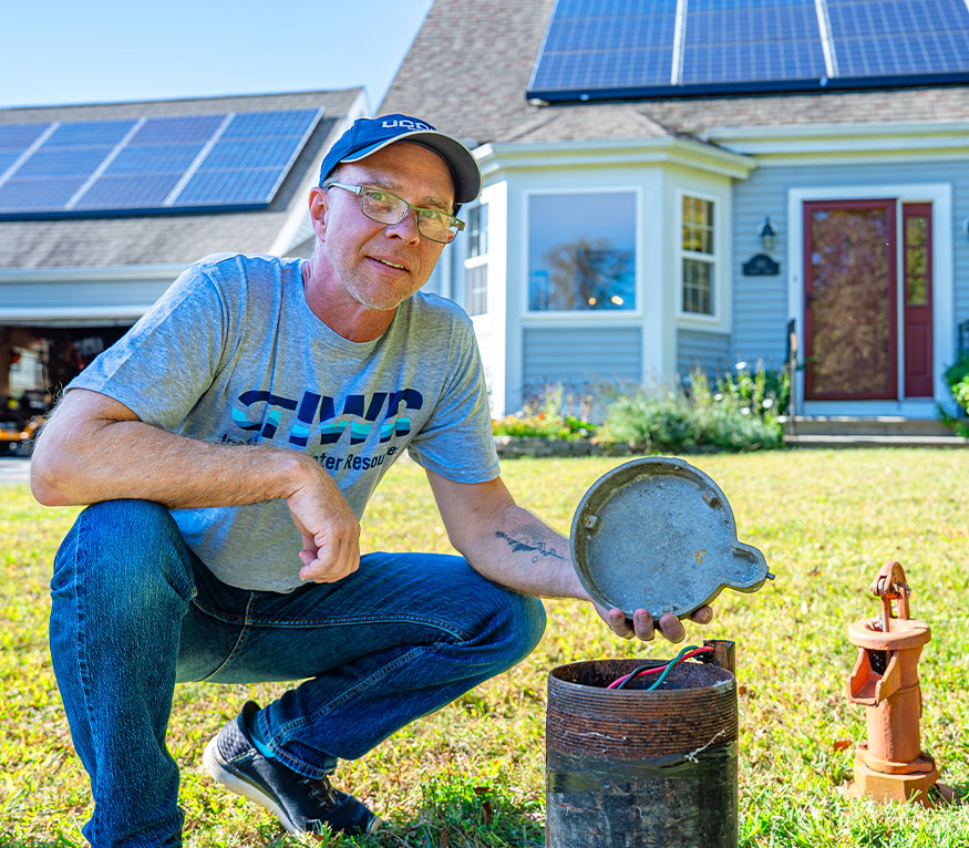 man lifting the lid on a residential home well.