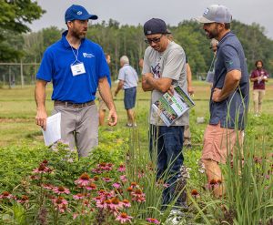three people talking in a pollinator garden.