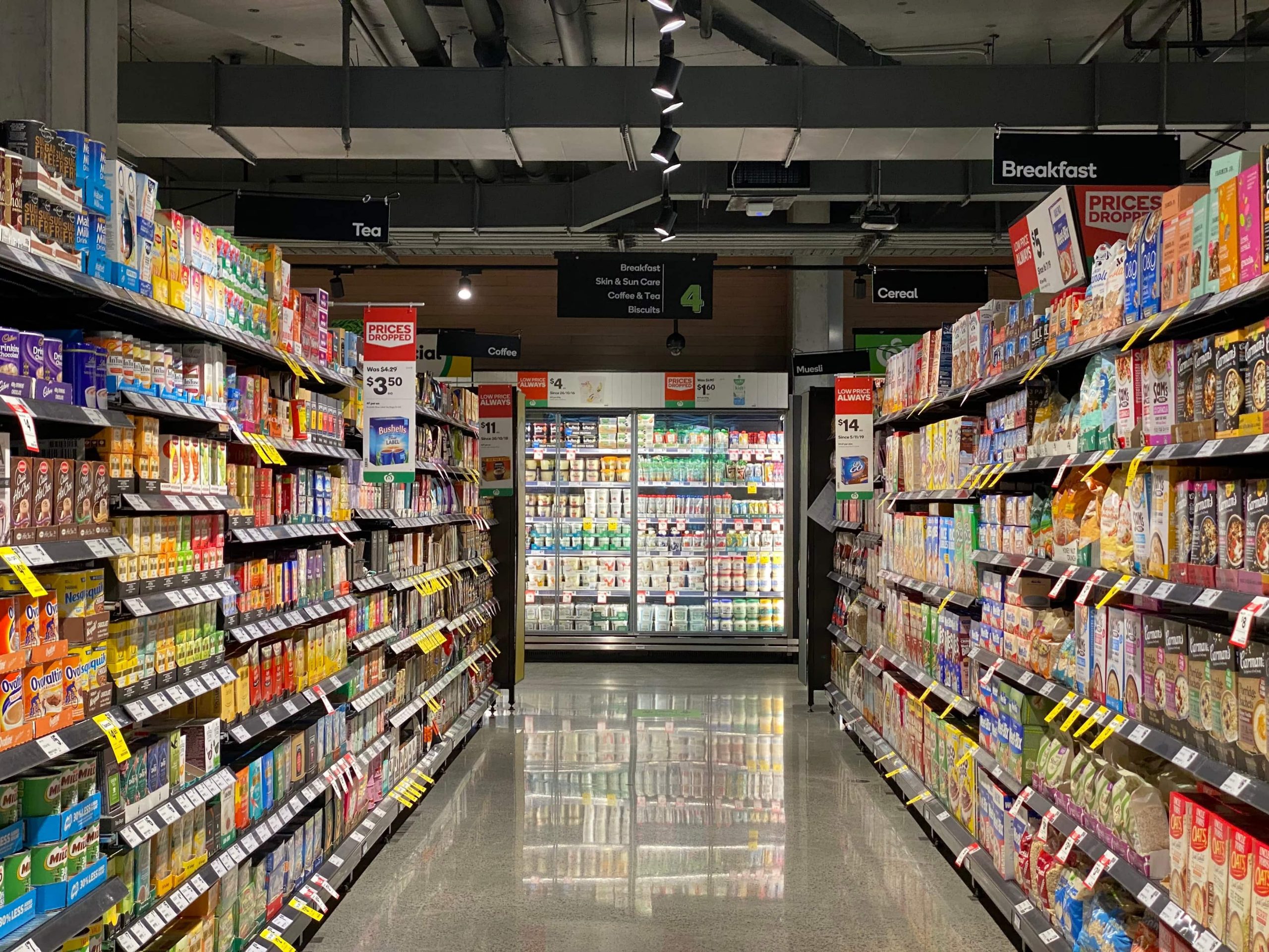 An image of a grocery store aisle with grey floors, and colorful packages on the shelves.
