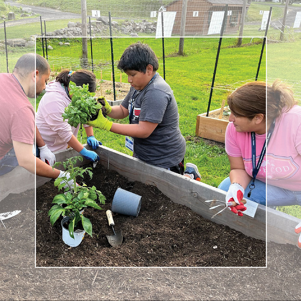 young boy and adults planting a small garden.