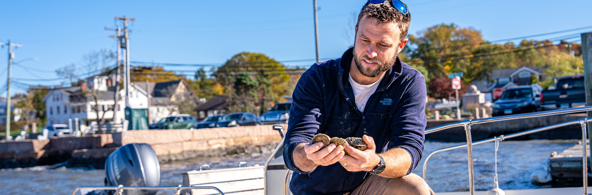 A fisherman on his boat holding some shellfish.