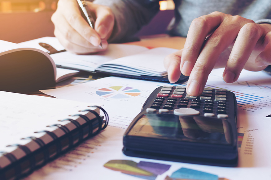calculator and paperwork on a desk with a persons hand